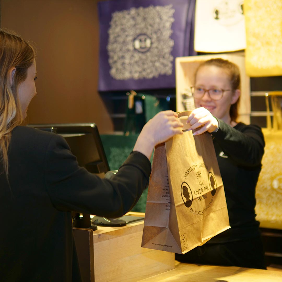 Medarbejder er overrækker en pose til en kunde I søsterne grene i Glostrup Shopingcenter